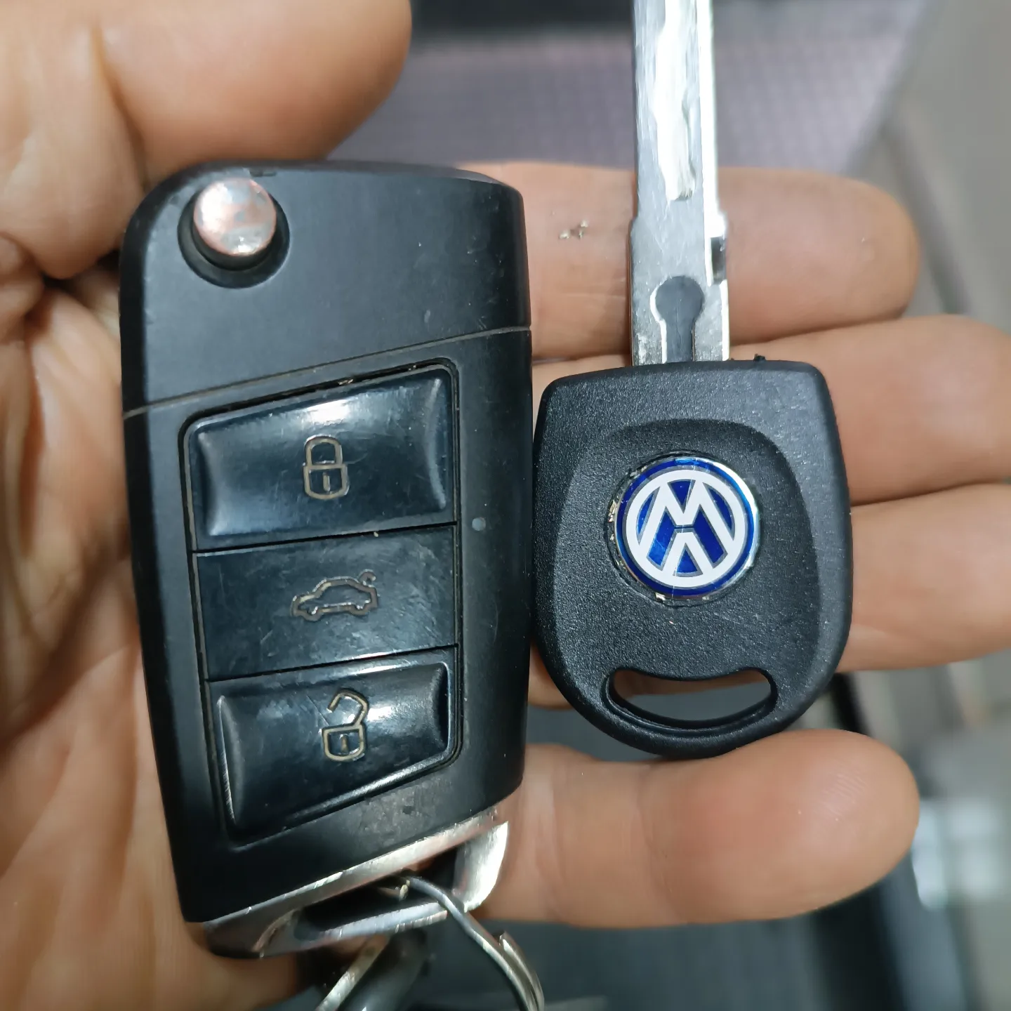 Chave canivete e chave codificada da Volkswagen na mão do chaveiro, na bancada